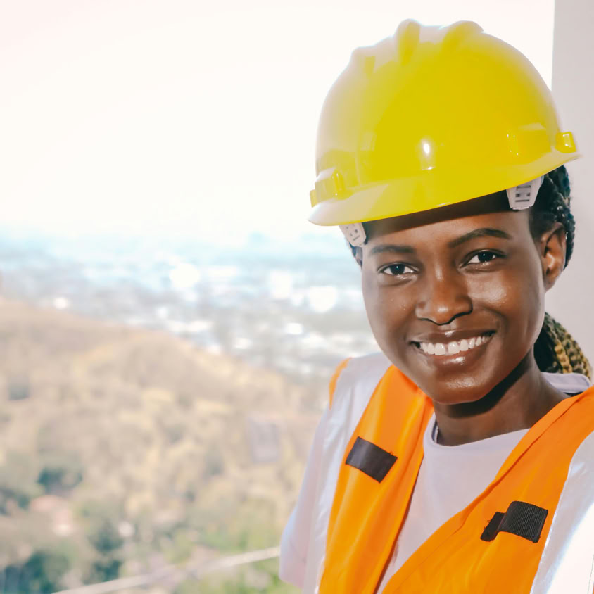 Black female engineer wearing safety gear and smiling, representing modern construction workforce.